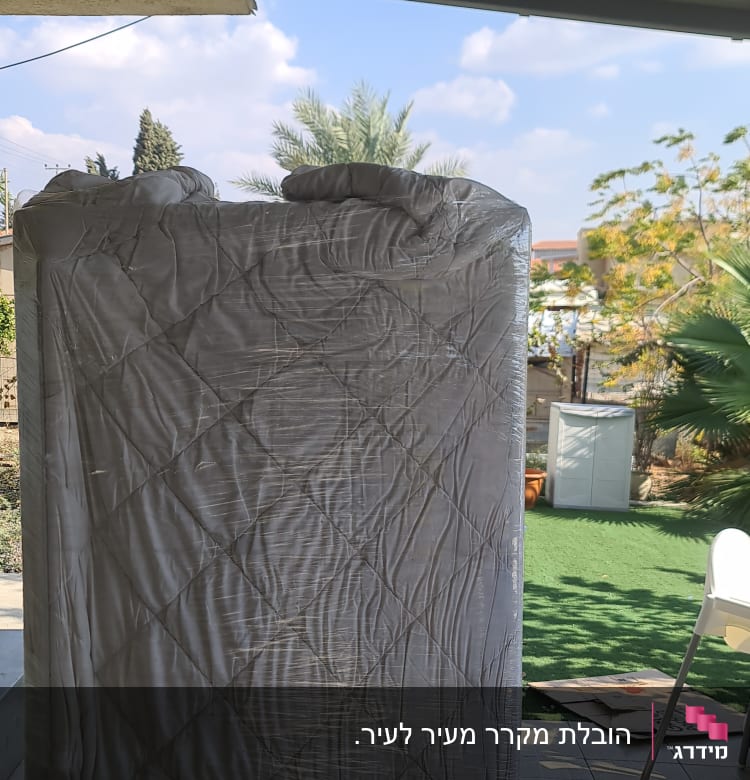 מזרן עטוף בניילון עומד בחוץ על מרפסת